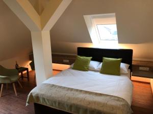 Un dormitorio con una cama con almohadas verdes y una ventana en Hotel Braun en Voitsberg