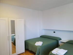 sypialnia z 2 zielonymi łóżkami i lustrem w obiekcie Camere Santa Rita w mieście San Giovanni Rotondo