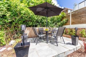 un patio con mesa, sillas y sombrilla en Guest Homes - Farningham Residence en Caterham