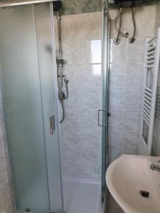 prysznic ze szklanymi drzwiami obok umywalki w obiekcie Camere Santa Rita w mieście San Giovanni Rotondo