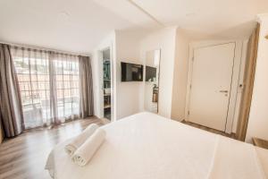 a white bedroom with a bed and a large window at dekatria rooms&aparts in Kaş