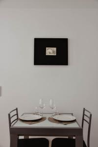 uma mesa com copos de vinho e uma foto na parede em Apartamento acolhedor e elegante em prédio típico - Self check in em Coimbra