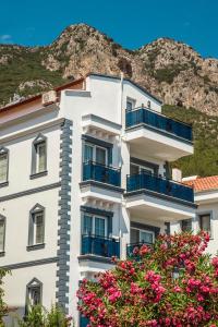 a white building with blue balconies in front of a mountain at dekatria rooms&aparts in Kaş