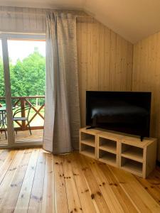 a living room with a television and a wooden floor at Brīvdienu māja VILCIŅI in Bernāti