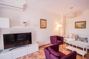 a living room with a large television and purple chairs at Cubo's Villa Yedra Guadalmar in Málaga