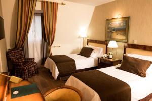 um quarto de hotel com duas camas e uma cadeira em Mayflower Suites em Buenos Aires