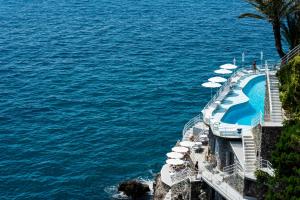 een zwembad met parasols naast het water bij Hotel Miramalfi in Amalfi