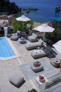 eine Gruppe von Liegestühlen und Sonnenschirmen neben einem Pool in der Unterkunft Irida Boutique Hotel in Parga