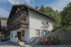 deux personnes assises à une table à l'extérieur d'une maison dans l'établissement APARTMA JAKOPIČ, à Zgornje Gorje
