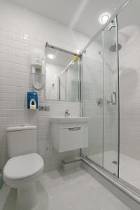 a white bathroom with a toilet and a shower at Alex Hotel on Bogatyrsky in Saint Petersburg