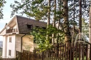 a small house behind a fence in front of trees at Casa Alice in Camigliatello Silano