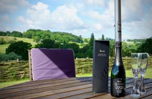 a bottle of wine and glasses on a wooden table at Hopeend Holidays Cottage in Great Malvern