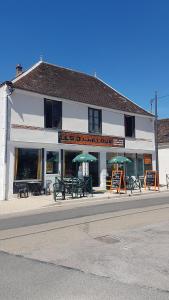 un bâtiment avec des tables et des parasols devant lui dans l'établissement Les 3 Cailloux Bar Restaurant, à Gurgy