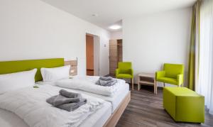 two beds in a room with two green chairs at Hotel Restaurant Zum Wacholderhain in Haselünne