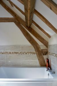 bagno con vasca bianca e soffitti in legno. di Hopeend Holidays Cottage a Great Malvern