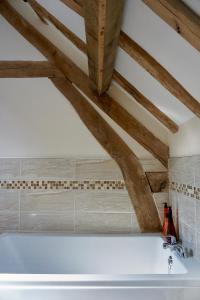 a white bath tub in a bathroom with wooden ceilings at Hopeend Holidays Cottage in Great Malvern