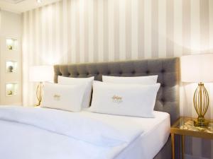 een wit bed met 2 witte kussens en 2 lampen bij Donau Lodge Boardinghouse in Straubing