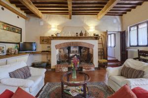 a living room with a fireplace with white couches and a table at Casa di Leo with pool in Radicondoli