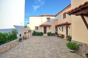 a courtyard of a house with benches and plants at Esperides Maisonettes in Votsi