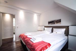 Un dormitorio con una gran cama blanca con una manta roja. en dat geele hus 1, en Büsum