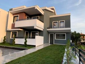 a house with a green lawn in front of it at L&S house in Nikiti