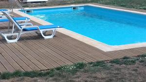 a deck with a chair and a swimming pool at Quinta do Favacal - Agroturismo - Serra da Estrela in Casegas