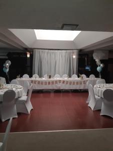 un salón de banquetes con mesas blancas y sillas blancas en Hôtel Aux Vieux Bardeaux, en Deschambault