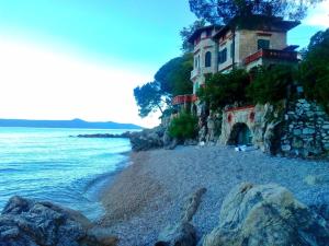 a house on a cliff next to the ocean at Apartments Lorinda in Mošćenička Draga