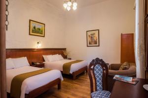 a hotel room with two beds and a chair at Majestad Hotel Boutique in Arequipa