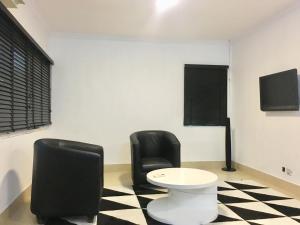 two black chairs and a table in a room at Sese Cottage in Ikeja