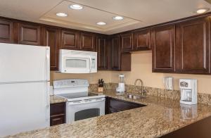 a kitchen with wooden cabinets and white appliances at WorldMark Havasu Dunes in Lake Havasu City