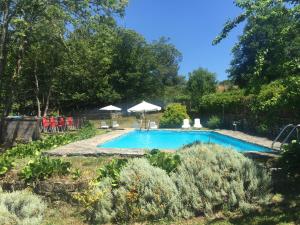 a swimming pool in a garden with umbrellas at Casa das Augas Santas in Aguas Santas