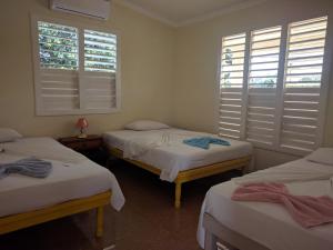 three beds in a room with windows and towels on them at Casa Carlos Valido in Viñales