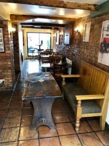una habitación con un banco y mesas en un restaurante en The Queens Head, en Stratford-upon-Avon