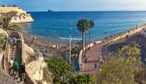 贝尼多姆APARTAMENTO EN EL CENTRO A UN MINUTO DE LA PLAYA的一群人在沙滩上与大海