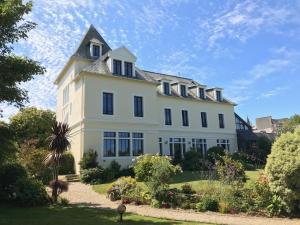 uma grande casa branca com uma torre no topo em Hotel de France em Saint-Pol-de-Léon