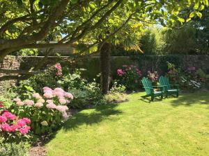 dos bancos verdes sentados en un jardín con flores en Hotel de France, en Saint-Pol-de-Léon