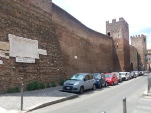 a row of cars parked next to a brick wall at Pietro's house in Rome