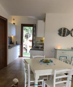 cocina con mesa blanca y sillas blancas en Villa Dante, en Castiadas