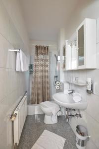 a white bathroom with a sink and a toilet at Pension Haus Aschgan in Egg am Faaker See