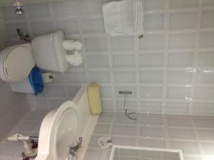 a white bathroom with a toilet and a sink at Hotel Arena Coco Playa in Boca Chica