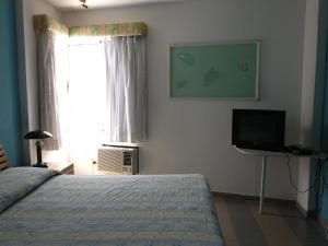 a bedroom with a bed and a tv and a window at Hotel Arena Coco Playa in Boca Chica