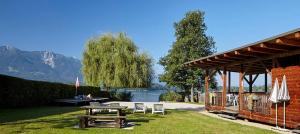 a picnic table and chairs next to a building with a lake at Pension Haus Aschgan in Egg am Faaker See