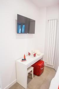 a white desk with a tv on a wall with a red suitcase at Kerbaker 14 in Naples