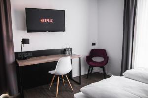 a hotel room with a bed, chair and television at Hayta Hotel Stuttgart Airport Messe in Filderstadt