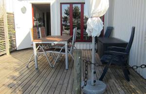 une terrasse couverte en bois avec une table et des chaises. dans l'établissement 1A, Stuga med 50m till strand, à Byxelkrok
