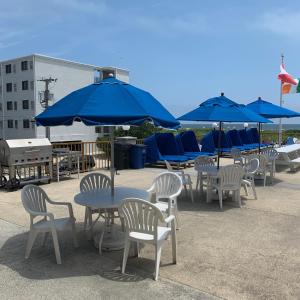 eine Gruppe von Tischen und Stühlen mit blauen Sonnenschirmen in der Unterkunft Roman Holiday Resort in North Wildwood