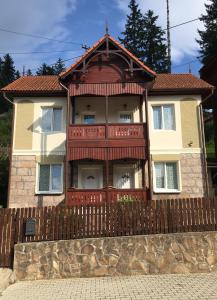 ein Haus mit einem Holzzaun davor in der Unterkunft Casa Karola Ház in Băile Tuşnad