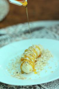 a person drizzling sauce on a food item on a plate at Oscar Inn Eco Resort in Águas de Lindoia