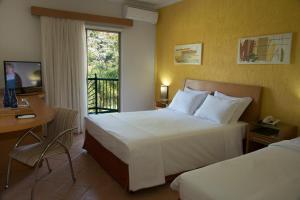 a hotel room with two beds and a television at Oscar Inn Eco Resort in Águas de Lindoia